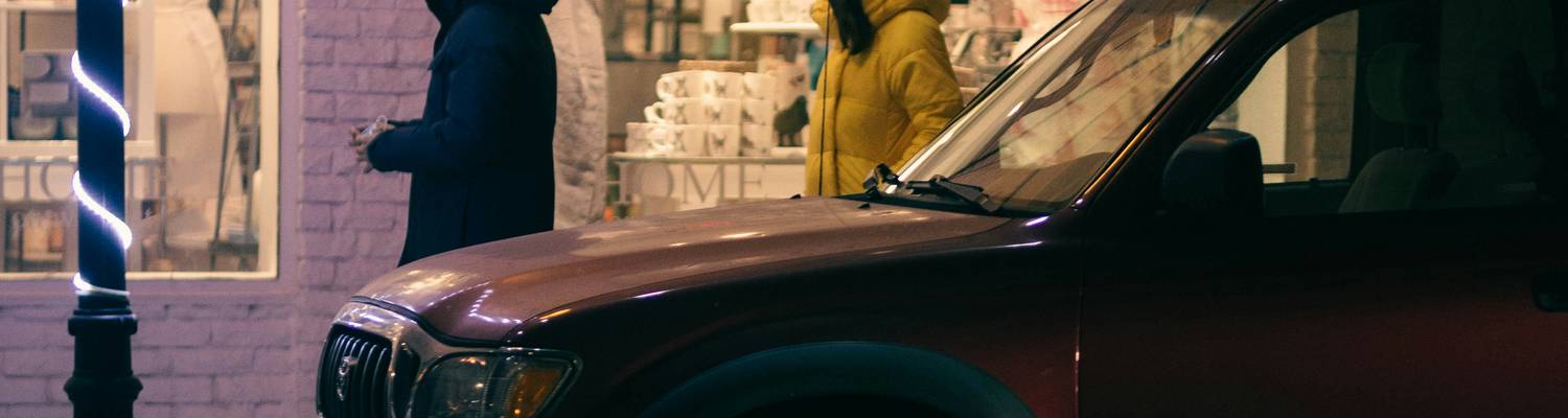A modern car parked in a Texas city street, with two people exchanging keys via a car sharing app, representing peer-to-peer car sharing. 