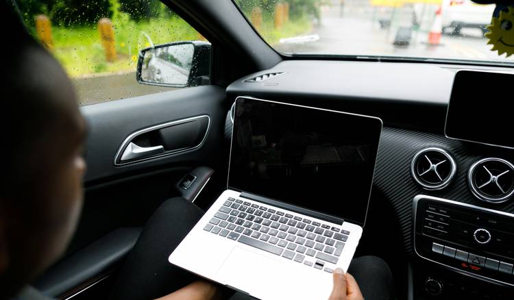 A Texas driver using a laptop to calculate car insurance rates, with paperwork and car keys on the table