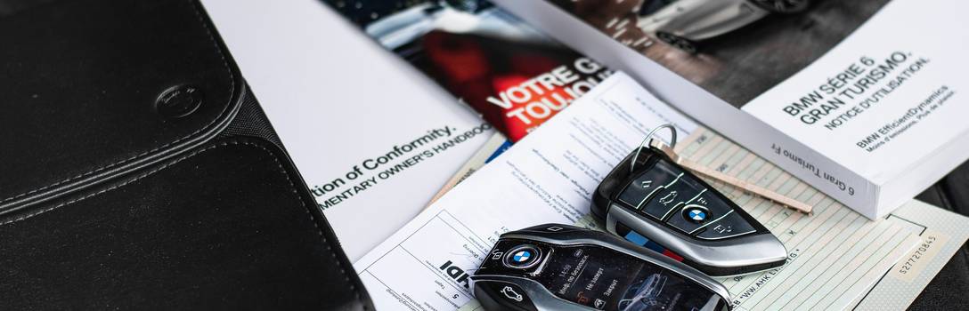 A close-up of a driver reviewing auto insurance paperwork, car keys and documents on a table