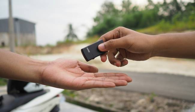 A Turo host handing car keys to a renter in Texas outside a house or parking lot, with insurance documents visible