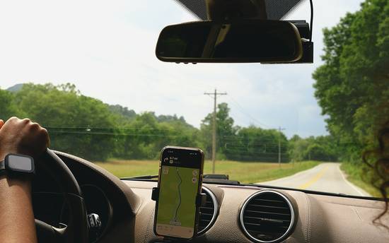 A car dashboard in Texas with a smartphone running a telematics insurance app or a plug-in insurance device visible. Modern, bright, technology-focused. 